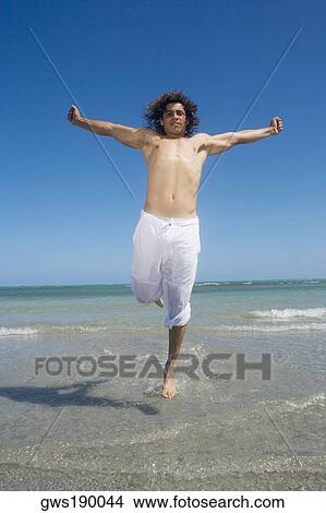 Mid adult man running on the beach with his arms outstretched View Large Photo Image Picture - Mid adult man running on the beach with his arms outstretched. Fotosearch
