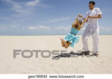 Mid adult man swinging her daughter on the beach View Large Photo Image Stock Image - Mid adult man swinging her daughter on the beach. Fotosearch