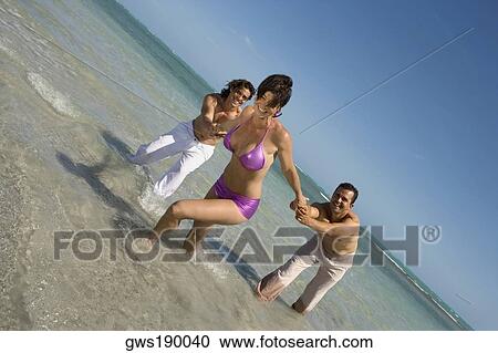 Mid adult woman pulling two mid adult men on the beach View Large Photo Image Stock Image - Mid adult woman pulling two mid adult men on the beach. Fotosearch