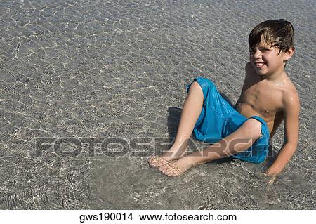 Portrait of a boy playing in water on the beach View Large Photo Image Picture - Portrait of a boy playing in water on the beach. Fotosearch