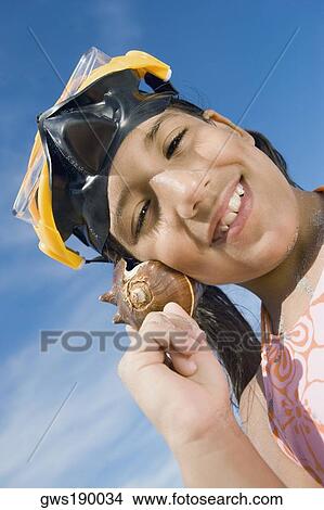 Portrait of a girl wearing a scuba mask and holding a conch shell to her ear View Large Photo Image Picture - Portrait of a girl wearing a scuba mask and holding a conch shell to her ear. Fotosearch