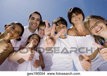 Portrait of a mid adult couple standing with five children making peace sign and thumbs up sign View Large Photo Image Picture - Portrait of a mid adult couple standing with five children making peace sign and thumbs up sign. Fotosearch