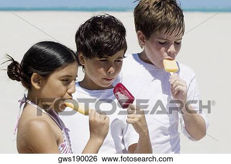 Two boys and a girl sucking ice-creams on the beach View Large Photo Image Stock Photograph - Two boys and a girl sucking ice-creams on the beach. Fotosearch
