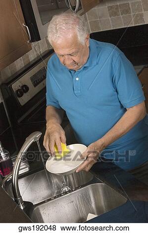 Close-up of a senior man cleaning a plate in the kitchen View Large Photo Image Stock Photo - Close-up of a senior man cleaning a plate in the kitchen. Fotosearch