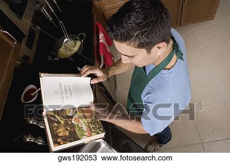 High angle view of a mid adult man preparing food with the help of a cookbook in the kitchen View Large Photo Image Stock Image - High angle view of a mid adult man preparing food with the help of a cookbook in the kitchen. Fotosearch