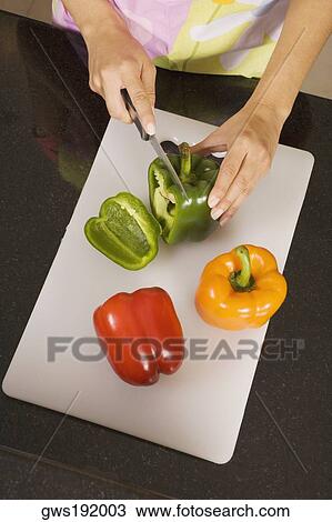High angle view of a woman cutting a green bell pepper on a cutting board View Large Photo Image Stock Image - High angle view of a woman cutting a green bell pepper on a cutting board. Fotosearch