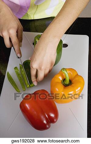 Stock Photo - High angle view of a woman cutting a green bell pepper. Fotosearch