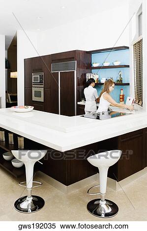 Stock Photography - Mature woman and her maid working in a kitchen. Fotosearch