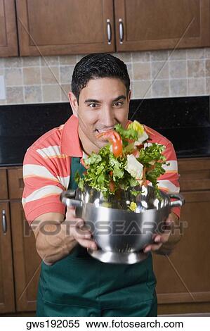 Stock Photography - Mid adult man mixing salad in a colander. Fotosearch
