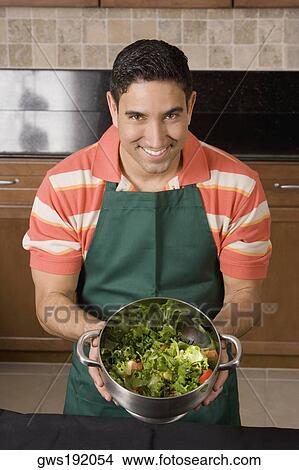 Picture - Portrait of a mid adult man mixing salad in a colander. Fotosearch