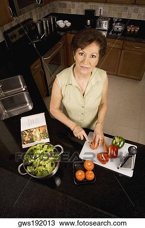 Portrait of a senior woman cutting vegetables on a cutting board in the kitchen View Large Photo Image Stock Image - Portrait of a senior woman cutting vegetables on a cutting board in the kitchen. Fotosearch
