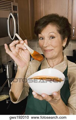 Portrait of a senior woman holding a bowl of tomato soup and a wooden spoon in the kitchen View Large Photo Image Stock Image - Portrait of a senior woman holding a bowl of tomato soup and a wooden spoon in the kitchen. Fotosearch