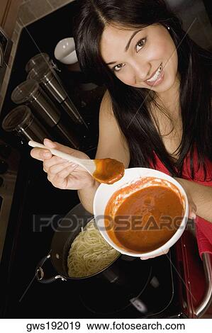 Stock Photo - Portrait of a young woman holding a bowl of tomato soup in the kitchen. Fotosearch