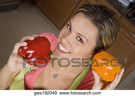 Portrait of a young woman holding red and yellow bell peppers and smiling View Large Photo Image Stock Photo - Portrait of a young woman holding red and yellow bell peppers and smiling. Fotosearch