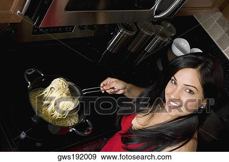 Portrait of a young woman preparing noodles in the kitchen View Large Photo Image Stock Photo - Portrait of a young woman preparing noodles in the kitchen. Fotosearch