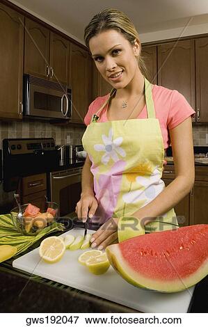 Portrait of a young woman standing at the kitchen counter cutting slices of an apple View Large Photo Image Stock Photo - Portrait of a young woman standing at the kitchen counter cutting slices of an apple. Fotosearch