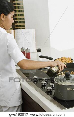 Rear view of a maid preparing food in the kitchen View Large Photo Image Stock Photo - Rear view of a maid preparing food in the kitchen. Fotosearch