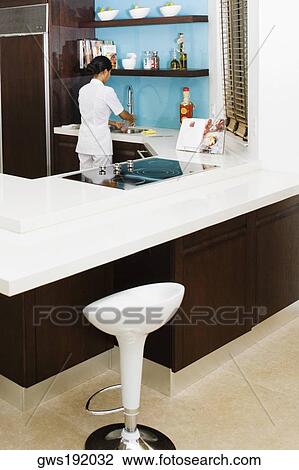 Rear view of a maid washing dishes in the kitchen View Large Photo Image Stock Image - Rear view of a maid washing dishes in the kitchen. Fotosearch