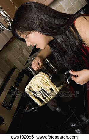 Young woman preparing noodles in the kitchen View Large Photo Image Stock Photograph - Young woman preparing noodles in the kitchen. Fotosearch