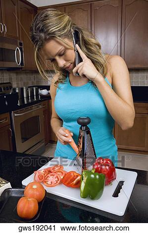 Young woman talking on a mobile phone and grating a carrot in the kitchen View Large Photo Image Stock Image - Young woman talking on a mobile phone and grating a carrot in the kitchen. Fotosearch