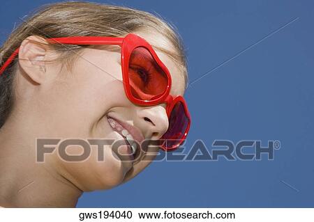Low angle view of a girl wearing red sunglasses and smiling View Large Photo Image Stock Image - Low angle view of a girl wearing red sunglasses and smiling. Fotosearch