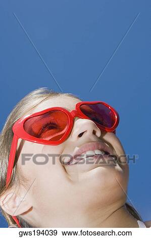 Low angle view of a girl wearing red sunglasses and smiling View Large Photo Image Stock Photo - Low angle view of a girl wearing red sunglasses and smiling. Fotosearch