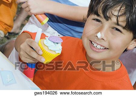 Portrait of a boy holding a cupcake and smiling View Large Photo Image Stock Photograph - Portrait of a boy holding a cupcake and smiling. Fotosearch