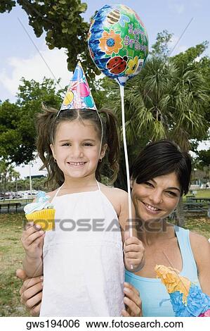 Portrait of a girl holding a balloon and smiling with her mother View Large Photo Image Stock Photograph - Portrait of a girl holding a balloon and smiling with her mother. Fotosearch