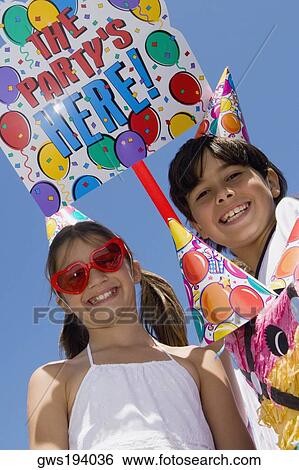 Portrait of a girl with her brother wearing birthday hats and smiling View Large Photo Image Stock Photograph - Portrait of a girl with her brother wearing birthday hats and smiling. Fotosearch