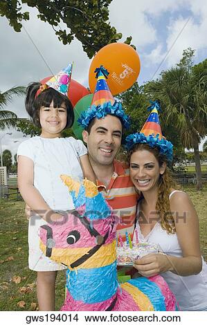 Portrait of a mid adult couple celebrating birthday with their daughter View Large Photo Image Picture - Portrait of a mid adult couple celebrating birthday with their daughter. Fotosearch