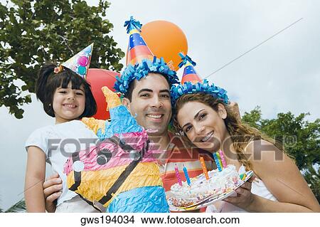 Portrait of a mid adult couple celebrating birthday with their daughter View Large Photo Image Picture - Portrait of a mid adult couple celebrating birthday with their daughter. Fotosearch