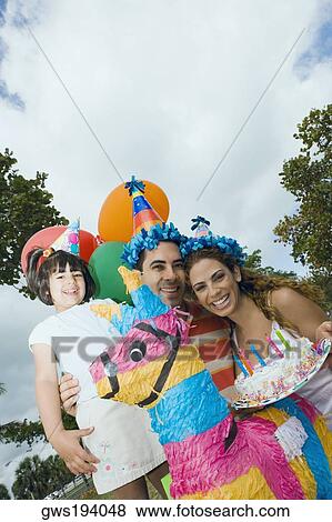 Stock Photo - Portrait of a mid adult couple celebrating birthday with their daughter. Fotosearch