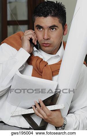 Picture - Architect holding a blueprint and talking on a mobile phone. Fotosearch