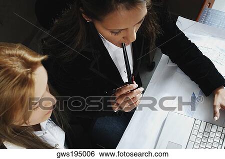 High angle view of two businesswomen working on a laptop View Large Photo Image Stock Photograph - High angle view of two businesswomen working on a laptop. Fotosearch
