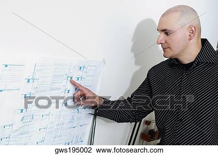 Stock Image - Male architect explaining a blueprint. Fotosearch