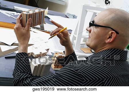 Rear view of an architect looking at a building's model View Large Photo Image Stock Photo - Rear view of an architect looking at a building's model. Fotosearch