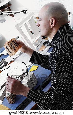 Stock Photo - Side profile of an architect holding an architectural model of a building and looking away. Fotosearch