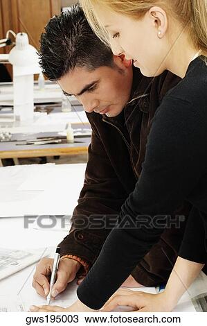 Stock Image - Side profile of two architects working together on a blueprint. Fotosearch