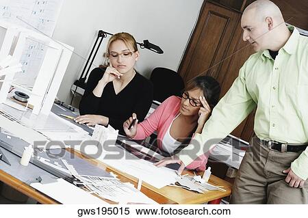 Stock Photography - Three architects working together on a blueprint. Fotosearch