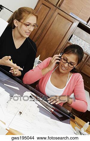 Two female architects drawing a blueprint in an office View Large Photo Image Picture - Two female architects drawing a blueprint in an office. Fotosearch