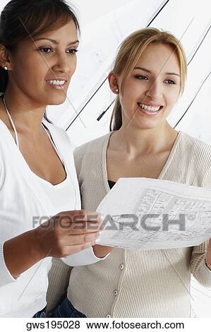 Stock Photo - Two female architects holding a blueprint and smiling. Fotosearch