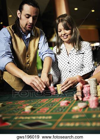Stock Photo - Casino worker arranging gambling chips for a young woman in a casino. Fotosearch