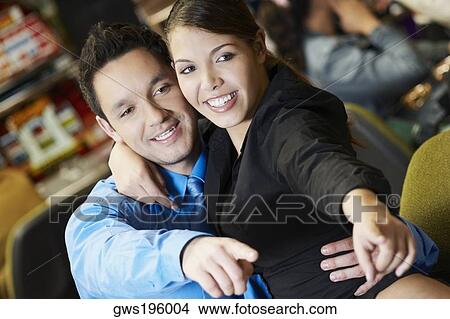 Close-up of a mid adult man with his arm around a teenage girl in a casino and pointing forward View Large Photo Image Picture - Close-up of a mid adult man with his arm around a teenage girl in a casino and pointing forward. Fotosearch