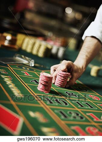 Close-up of a person's hand placing gambling chips on a gambling table View Large Photo Image Stock Image - Close-up of a person's hand placing gambling chips on a gambling table. Fotosearch