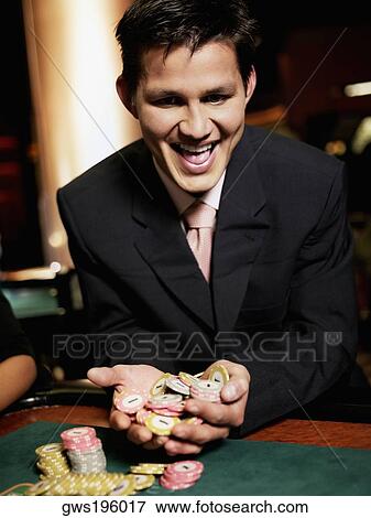 Close-up of a young man cheering with handful of gambling chips in a casino View Large Photo Image Stock Photo - Close-up of a young man cheering with handful of gambling chips in a casino. Fotosearch