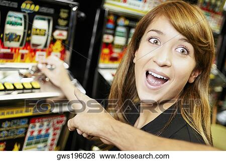Close-up of a young woman playing on a slot machine with another person pointing at it View Large Photo Image Stock Photo - Close-up of a young woman playing on a slot machine with another person pointing at it. Fotosearch