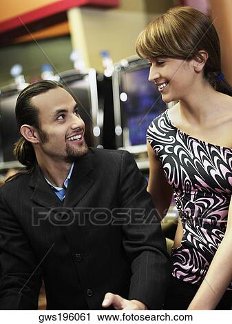 Mid adult man and a young woman looking at each other in a casino View Large Photo Image Stock Image - Mid adult man and a young woman looking at each other in a casino. Fotosearch