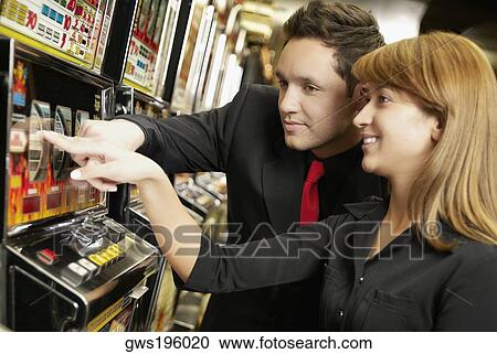 Mid adult man and a young woman playing on a slot machine View Large Photo Image Stock Image - Mid adult man and a young woman playing on a slot machine. Fotosearch