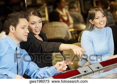 Stock Image - Mid adult man with a teenage girl and a young woman in a casino. Fotosearch
