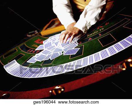 Picture - Mid section view of a casino worker shuffling playing cards on a gambling table. Fotosearch